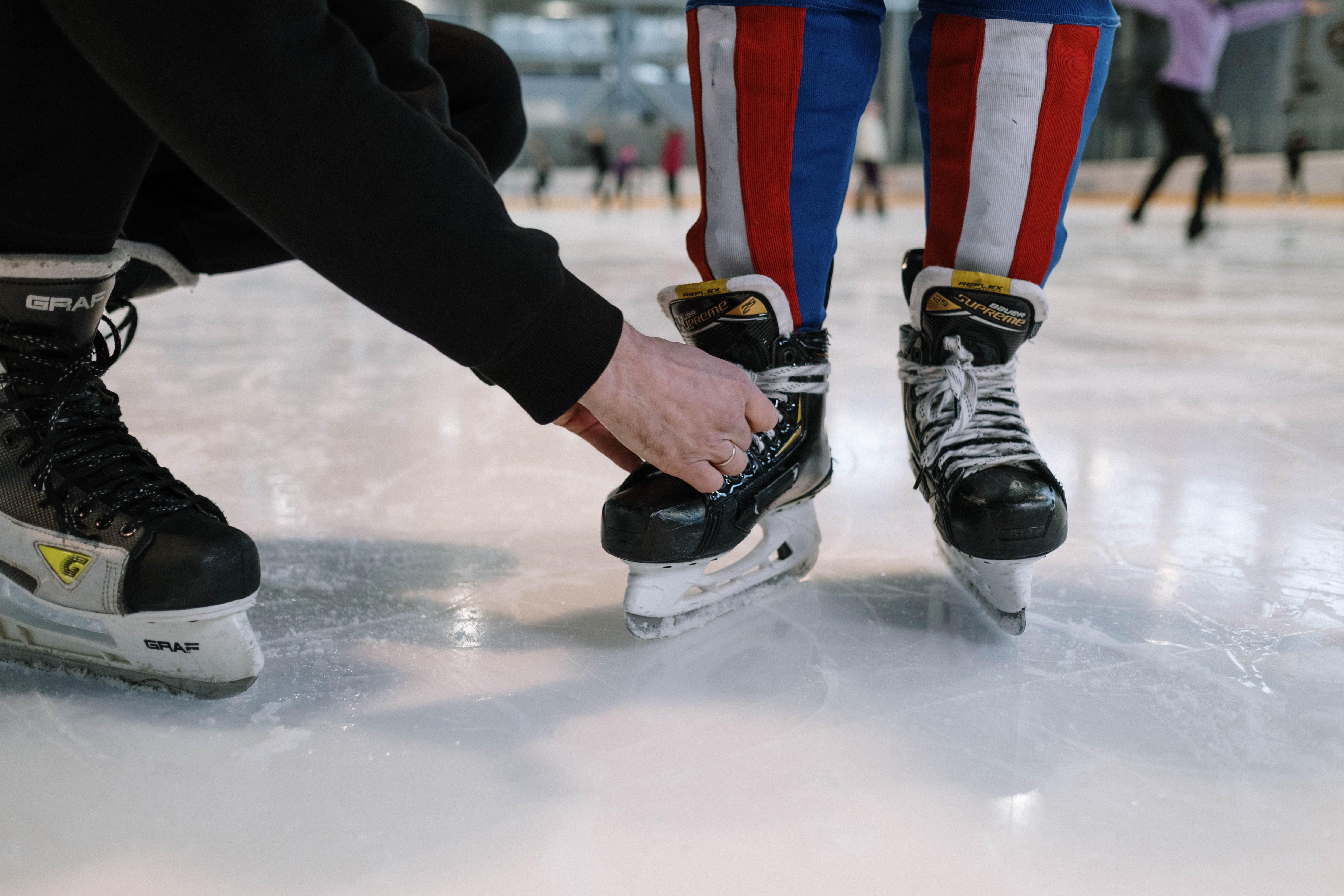 Photograph of a person tying another person's ice skates